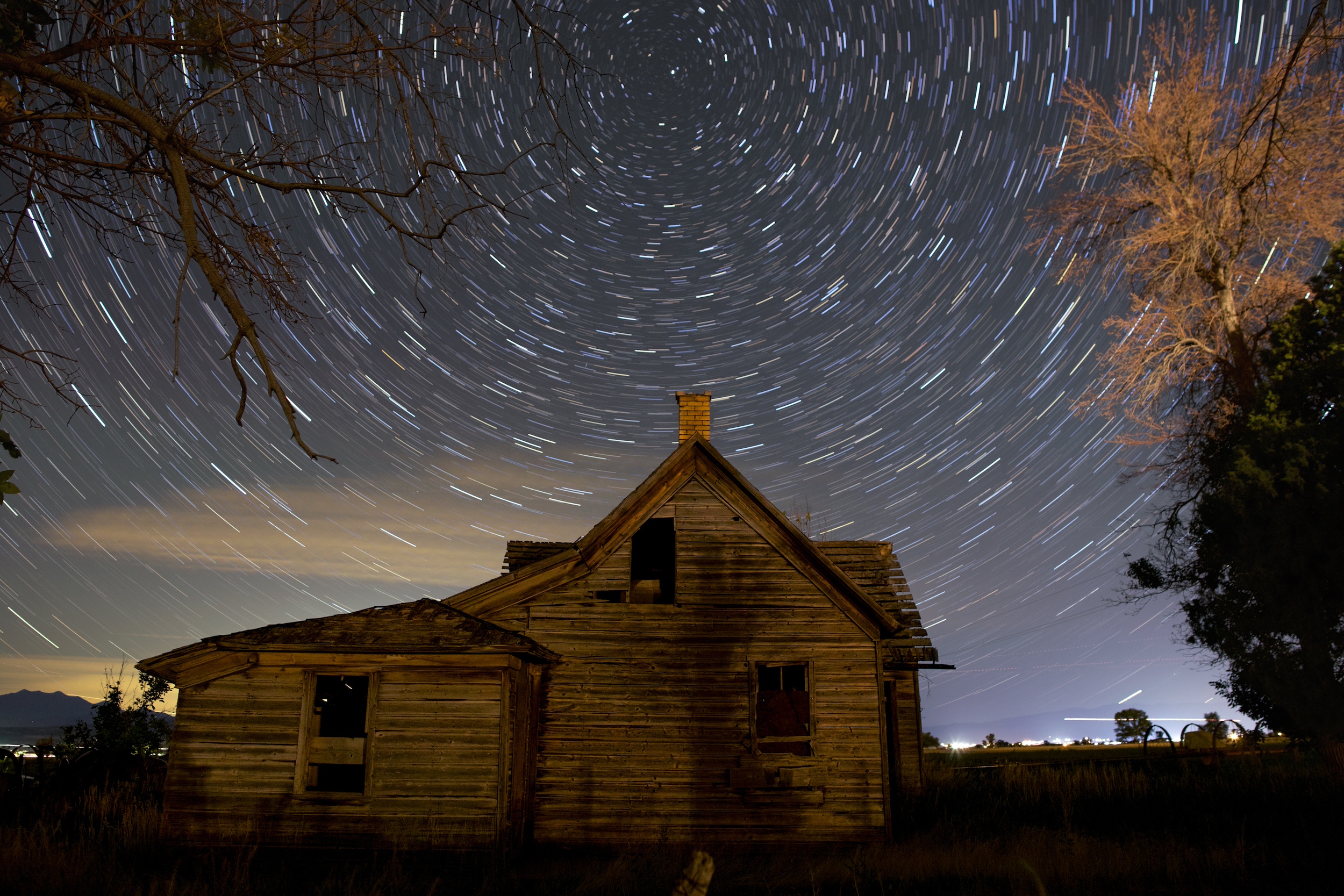 slihouetted towers of sandstone at night. in the sky is a diffuse glow of yellow and red