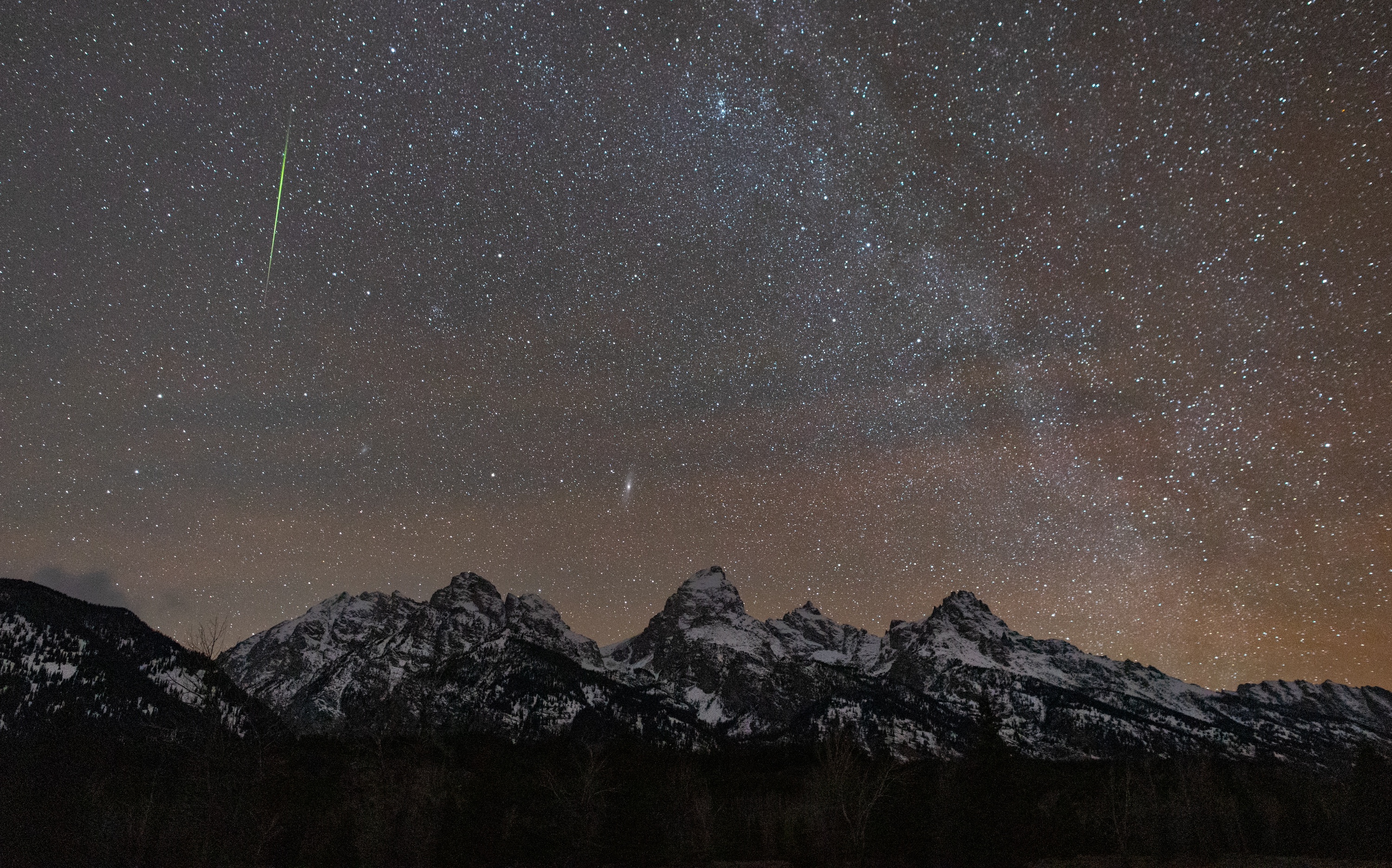 slihouetted towers of sandstone at night. in the sky is a diffuse glow of yellow and red