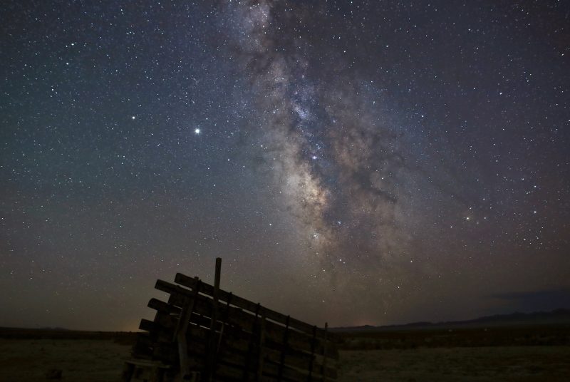 a starry night sky is visible over wooden fencing