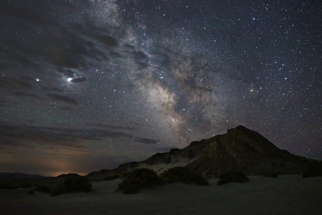 starry sky and clouds over a peak in a sandy desert